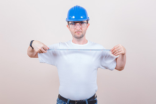 Construction worker holding measuring tape in t-shirt, jeans, he